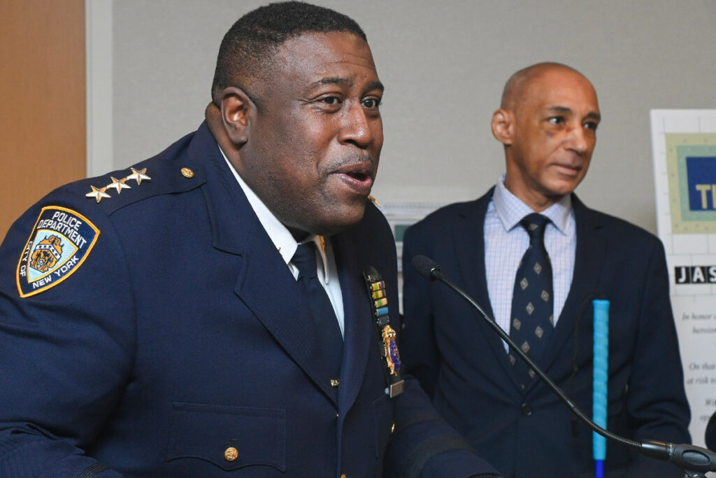 Jeffrey Maddrey in a blue police uniform speaking at a microphone.